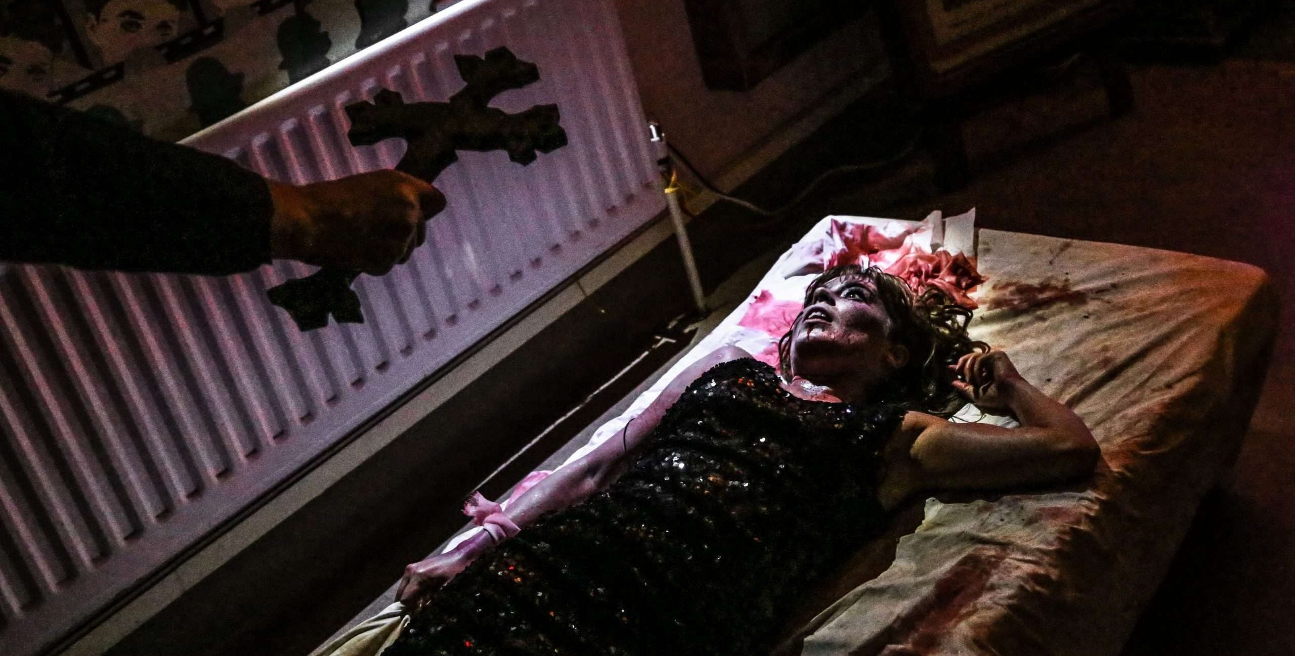 A woman laying on a bed with a knife in her hand.