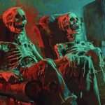 Two skeletons sit in armchairs watching a television in a room with a colorful, abstract background.
